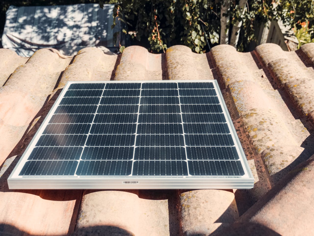 creative-02 A single solar panel on a rustic tiled roof gleaming in sunlight. Eco-friendly energy.
