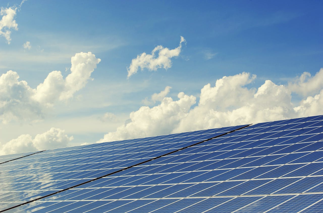 mobile-02 Sleek modern solar panels under a vibrant blue sky with clouds, symbolizing clean energy.
